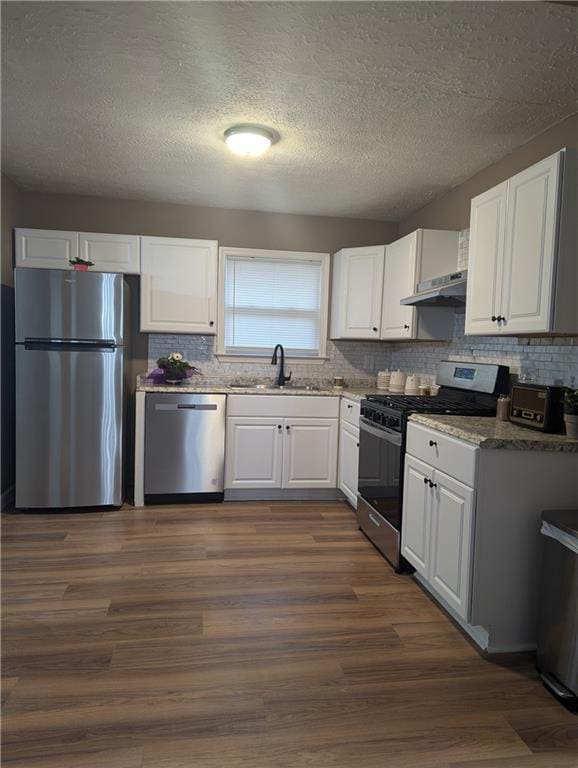 kitchen featuring appliances with stainless steel finishes, sink, backsplash, white cabinets, and dark hardwood / wood-style flooring