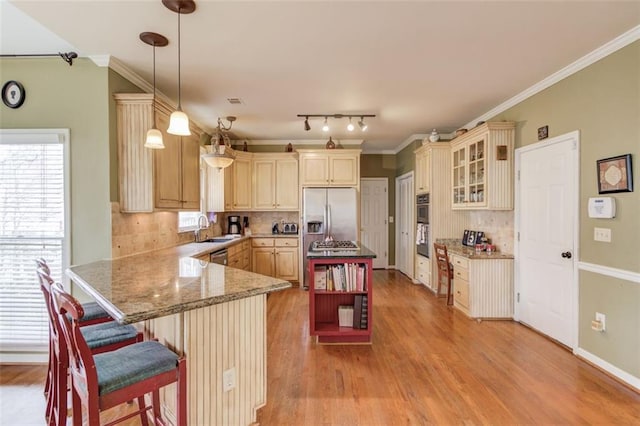 kitchen with a breakfast bar, sink, stainless steel fridge, kitchen peninsula, and pendant lighting