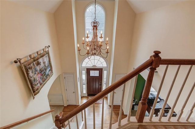 interior space featuring a notable chandelier, wood-type flooring, and a high ceiling