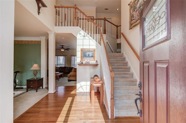 entrance foyer featuring light wood-type flooring, ornamental molding, a high ceiling, and ornate columns