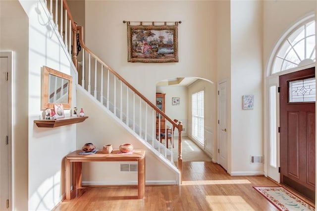 foyer entrance with a towering ceiling and light hardwood / wood-style floors