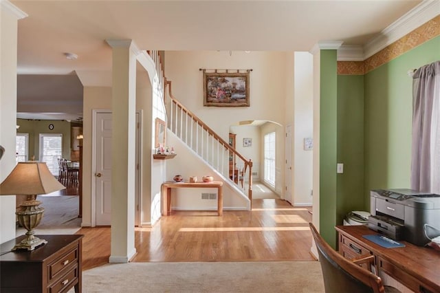 foyer with ornamental molding and light hardwood / wood-style floors