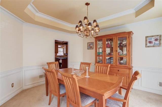 carpeted dining area featuring ornamental molding, a raised ceiling, and a chandelier