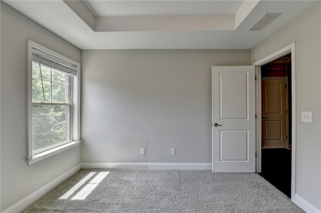 unfurnished room featuring carpet flooring, plenty of natural light, baseboards, and a raised ceiling