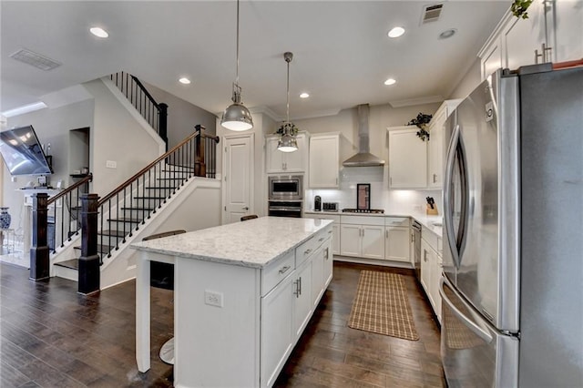 kitchen featuring appliances with stainless steel finishes, wall chimney exhaust hood, dark wood finished floors, a center island, and white cabinets