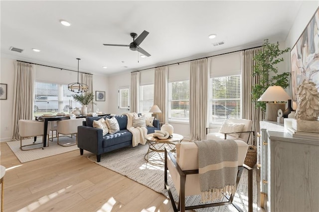 living area featuring a healthy amount of sunlight, wood finished floors, and ceiling fan with notable chandelier