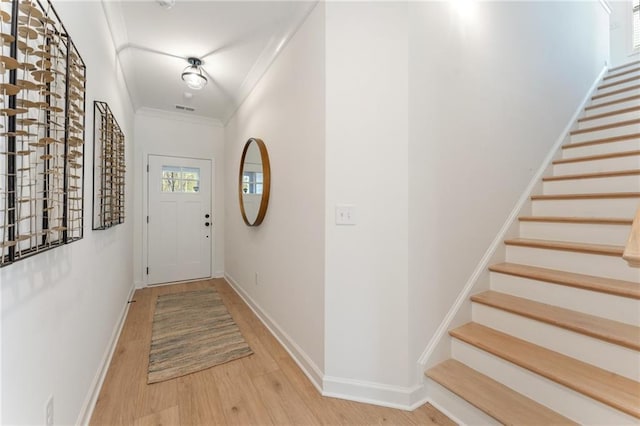 interior space featuring baseboards, ornamental molding, stairs, and wood finished floors