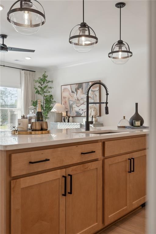 bar with pendant lighting, a sink, and light wood-style floors