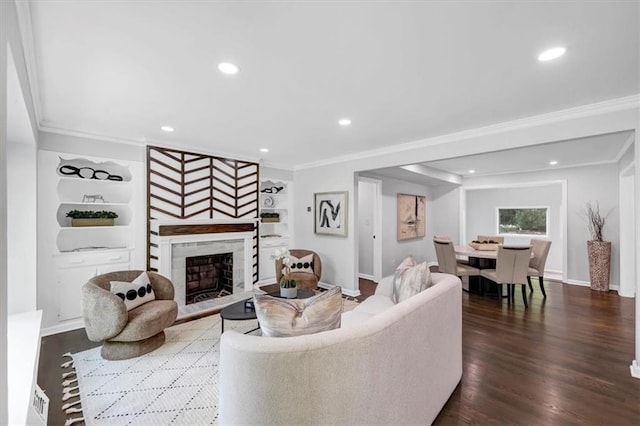 living room featuring built in shelves, dark wood-type flooring, ornamental molding, and a fireplace