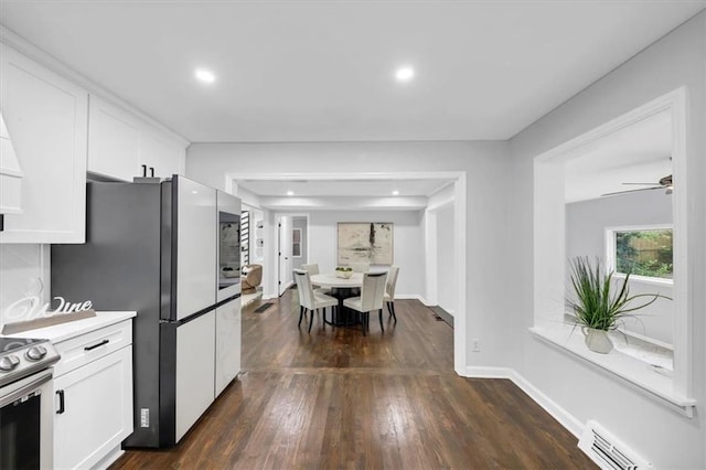 kitchen with dark wood-style floors, baseboards, freestanding refrigerator, stainless steel range with electric stovetop, and white cabinets