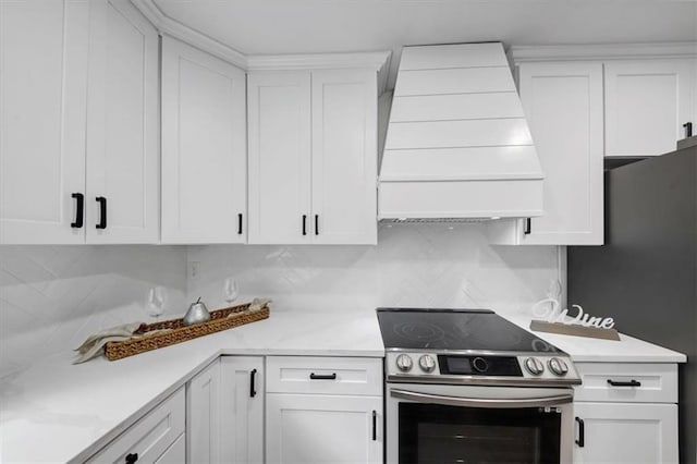 kitchen with backsplash, custom range hood, stainless steel electric stove, and white cabinets