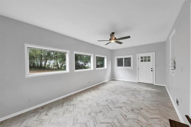 empty room featuring ceiling fan and baseboards