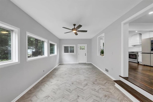 interior space with baseboards, visible vents, and ceiling fan