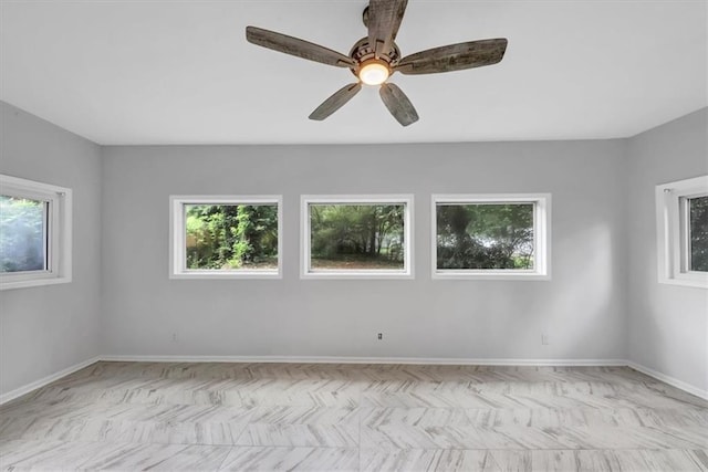 spare room with baseboards, plenty of natural light, and ceiling fan