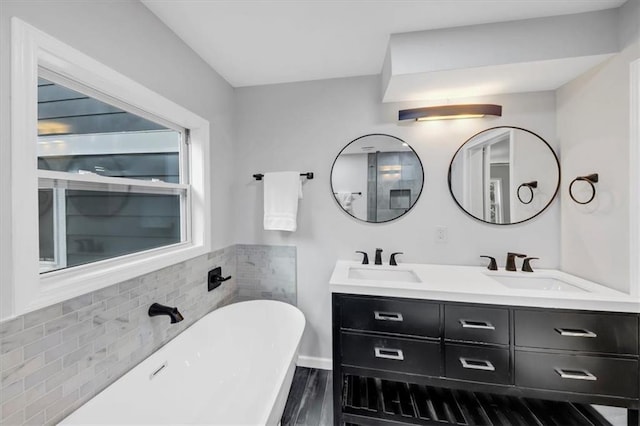 full bath featuring a freestanding bath, double vanity, wood finished floors, and a sink