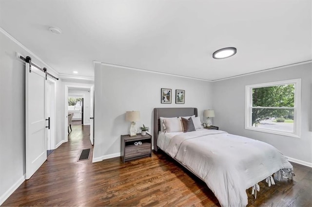 bedroom with a barn door, visible vents, wood finished floors, and crown molding