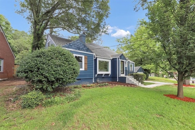 view of front of property with a chimney, a front yard, and roof with shingles