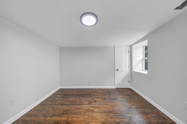 spare room with baseboards and wood finished floors