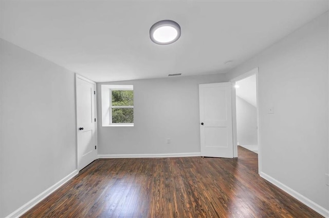 empty room with baseboards, dark wood finished floors, and vaulted ceiling