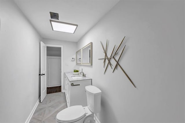 bathroom with toilet, vanity, and baseboards