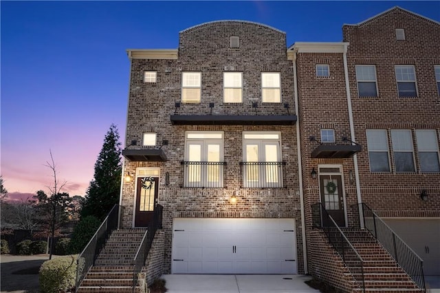 townhome / multi-family property featuring concrete driveway, brick siding, and an attached garage