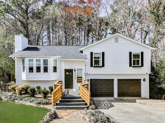 split foyer home with driveway, an attached garage, a chimney, and board and batten siding