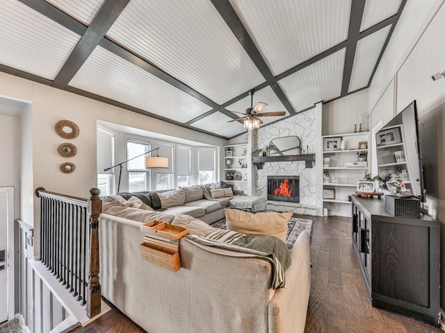 living room featuring lofted ceiling with beams, built in shelves, dark wood-style flooring, a fireplace, and a ceiling fan