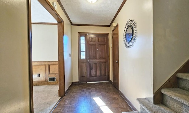 foyer entrance with dark parquet flooring, crown molding, and a textured ceiling