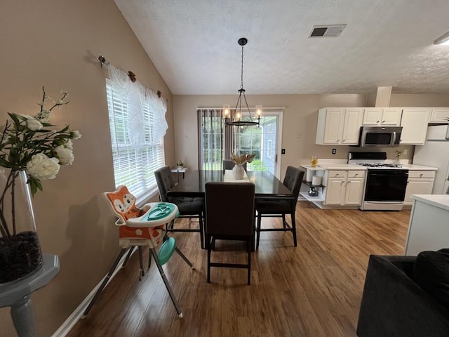 2529 Feathertree Ln, Lawrenceville, GA 30044 - dining space with wood finished floors, a chandelier, a textured ceiling, baseboards, and lofted ceiling