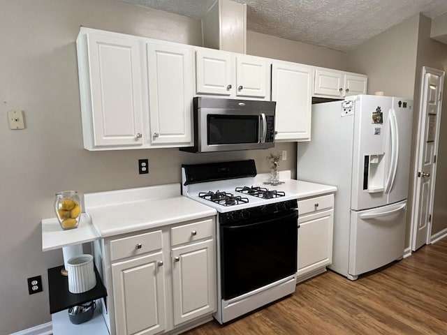 2529 Feathertree Ln, Lawrenceville, GA 30044 - kitchen featuring gas range oven, stainless steel microwave, white refrigerator with ice dispenser, white cabinets, and a textured ceiling