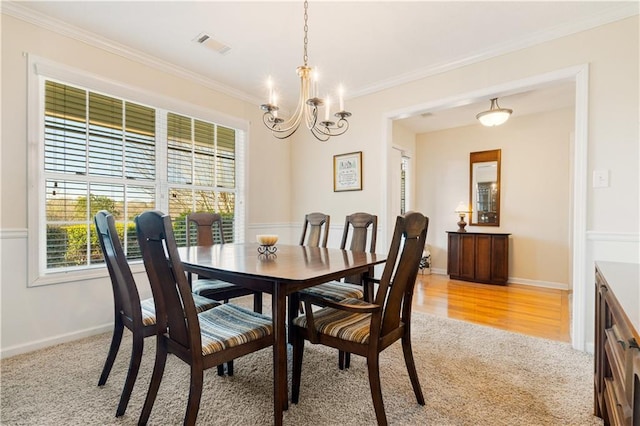 dining area with light carpet, a notable chandelier, and ornamental molding