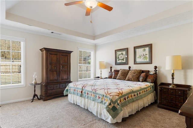 carpeted bedroom featuring a tray ceiling, ornamental molding, and ceiling fan