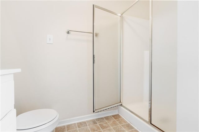 bathroom featuring a shower with shower door and toilet