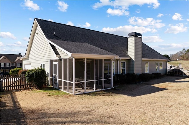 rear view of house featuring a yard and a sunroom