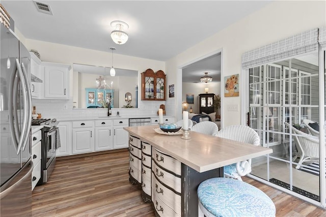 kitchen featuring wood finished floors, a kitchen bar, light countertops, a sink, and appliances with stainless steel finishes