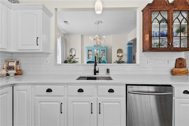 kitchen with visible vents, tasteful backsplash, stainless steel dishwasher, a sink, and a notable chandelier