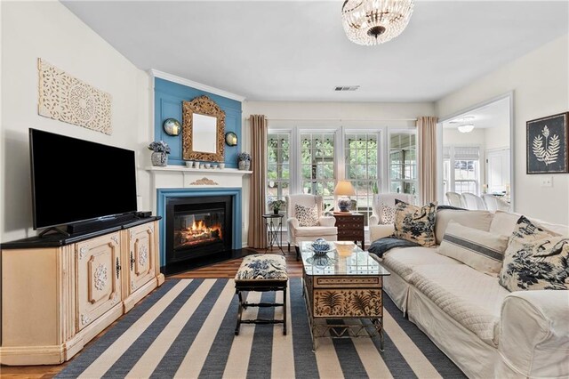 living area with a fireplace with flush hearth, visible vents, plenty of natural light, and wood finished floors