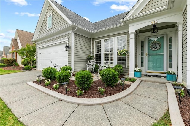 entrance to property featuring a shingled roof and driveway