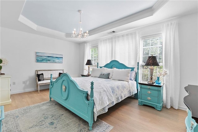 bedroom featuring a notable chandelier, light wood-type flooring, a tray ceiling, visible vents, and ornamental molding