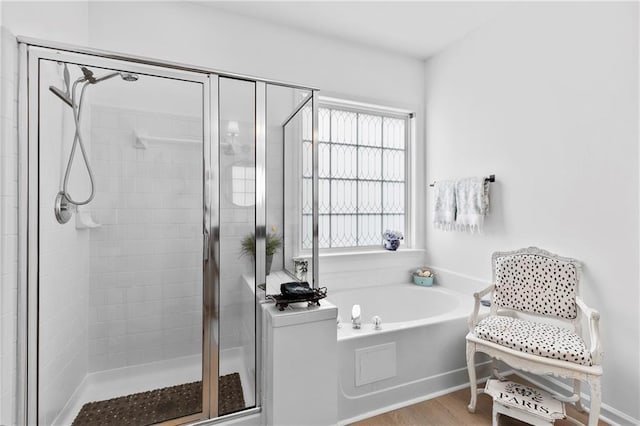 bathroom featuring a stall shower, a garden tub, and wood finished floors