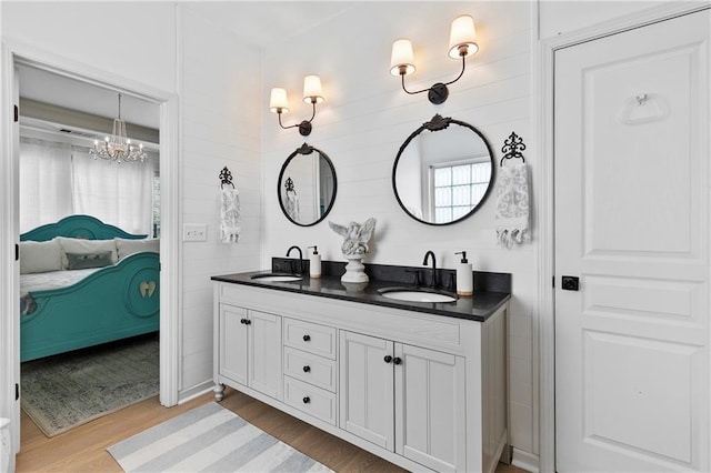 ensuite bathroom featuring ensuite bathroom, a sink, wood finished floors, and double vanity