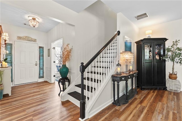 entrance foyer featuring stairway, baseboards, wood finished floors, and visible vents