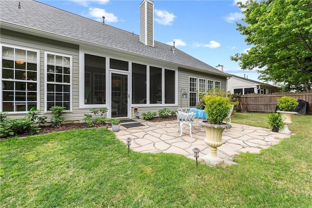 rear view of property with fence, a chimney, a shingled roof, a patio area, and a yard