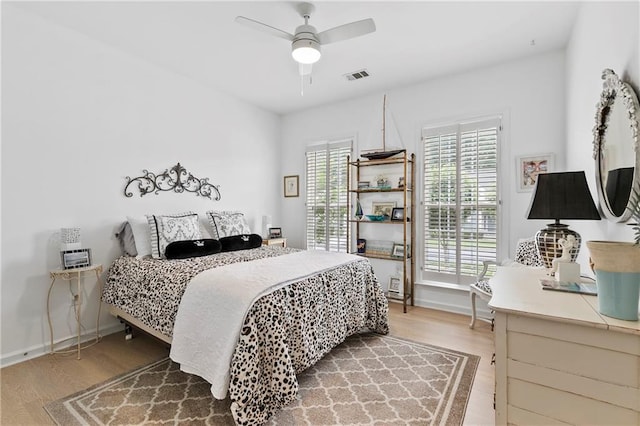 bedroom with visible vents, a ceiling fan, baseboards, and wood finished floors