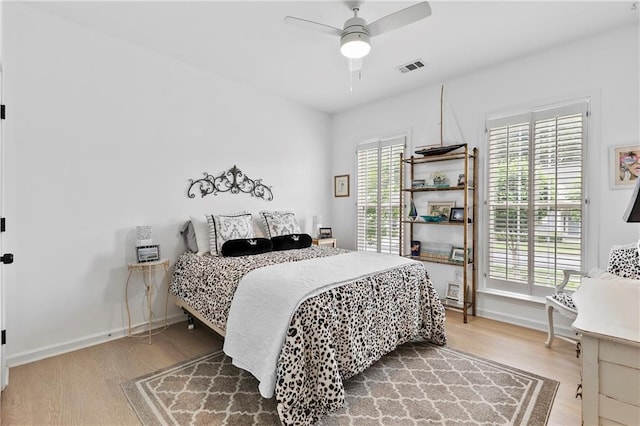 bedroom with a ceiling fan, baseboards, visible vents, and wood finished floors