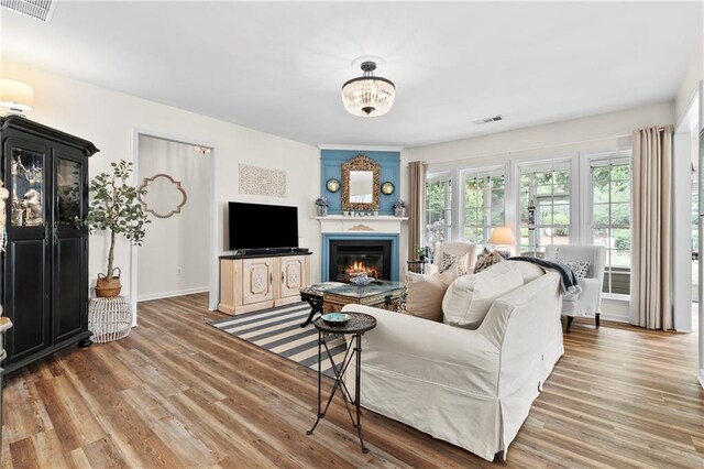 living room featuring visible vents, baseboards, a glass covered fireplace, and wood finished floors