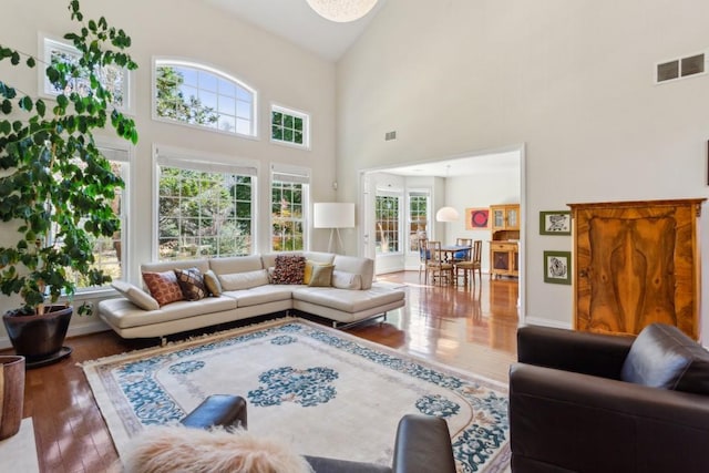 living room with hardwood / wood-style floors and a towering ceiling