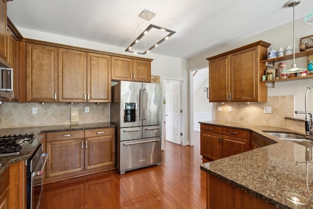 kitchen featuring decorative backsplash, stainless steel appliances, hanging light fixtures, and dark stone counters