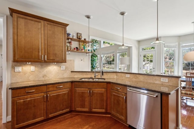 kitchen featuring dark stone countertops, dark hardwood / wood-style flooring, decorative light fixtures, stainless steel dishwasher, and kitchen peninsula