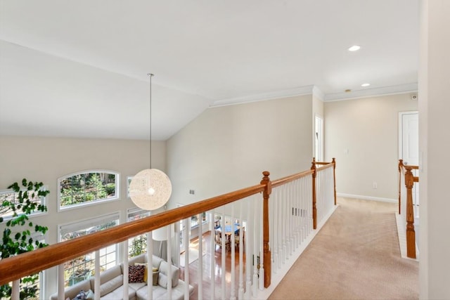 hallway with vaulted ceiling, ornamental molding, and light colored carpet